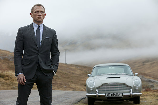 Daniel Craig stands near an Aston Martin in the Scottish Highlands.